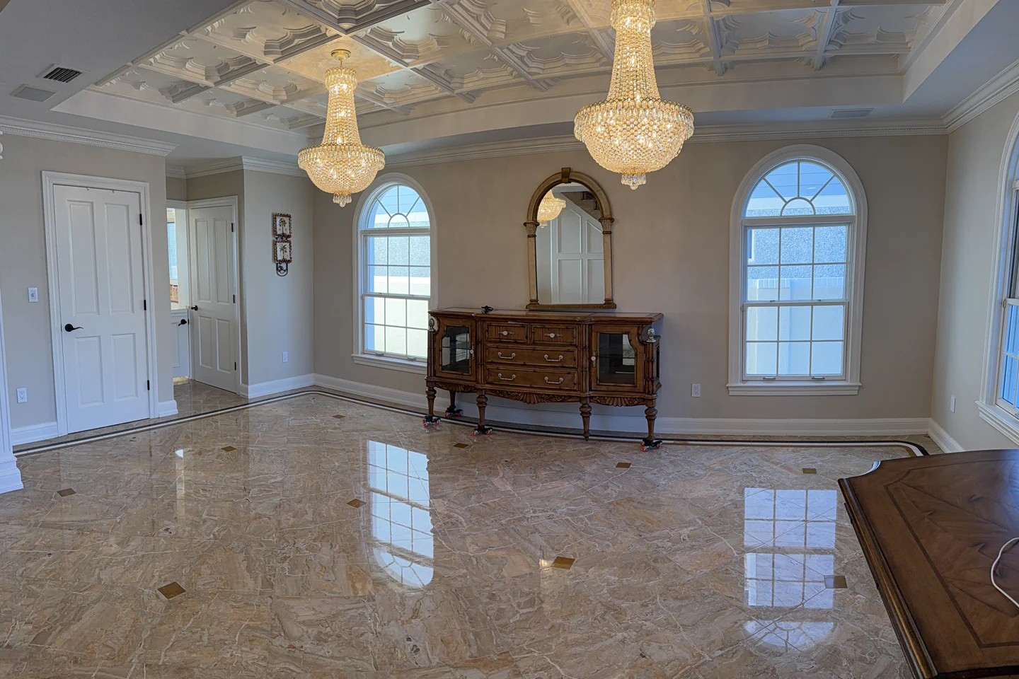 Polished marble floor with brass inlay accents reflecting two chandeliers in a Tampa Bay dining room