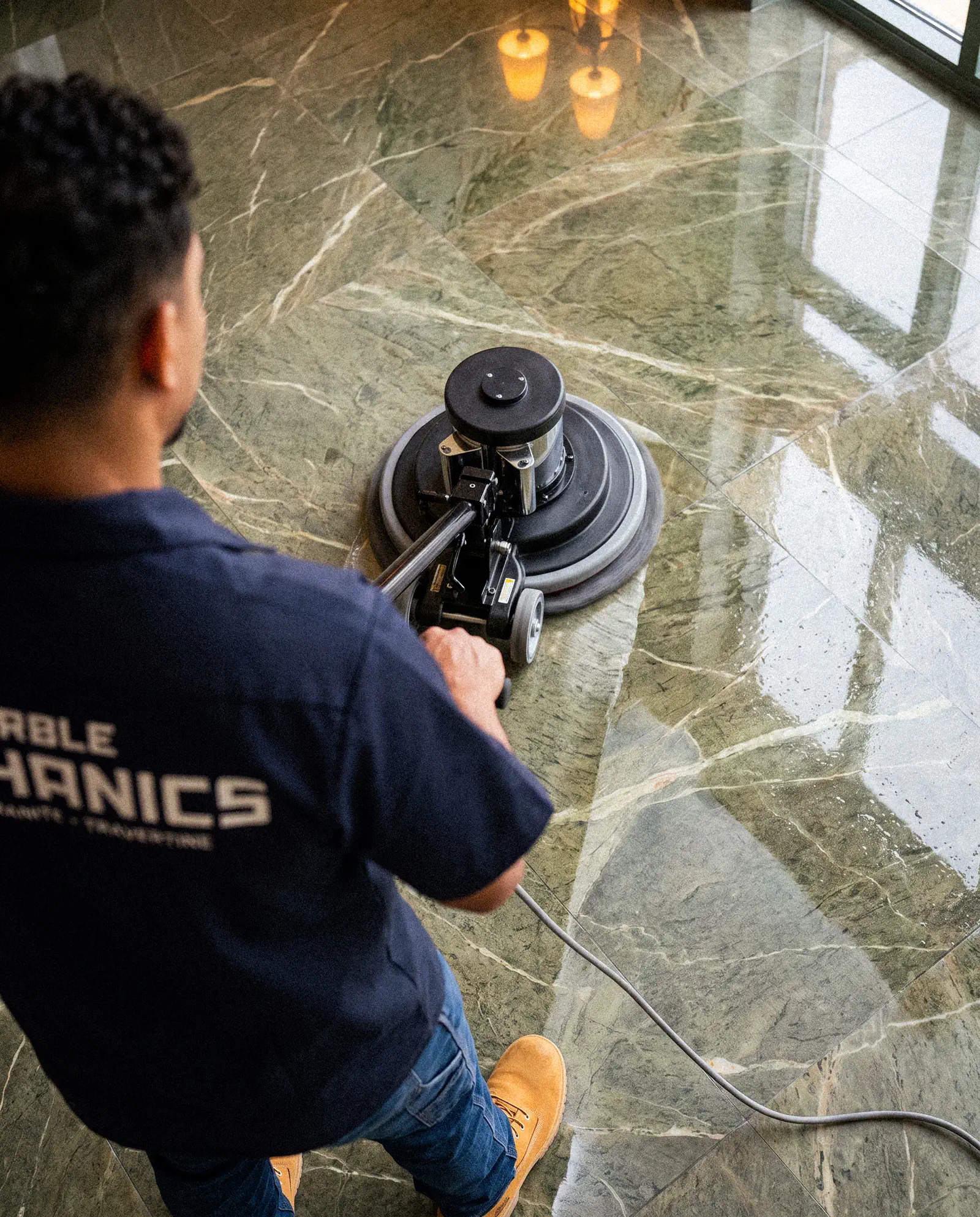 Marble polishing in Sarasota: a Marble Mechanics technician running a rotary polisher across a green marble floor