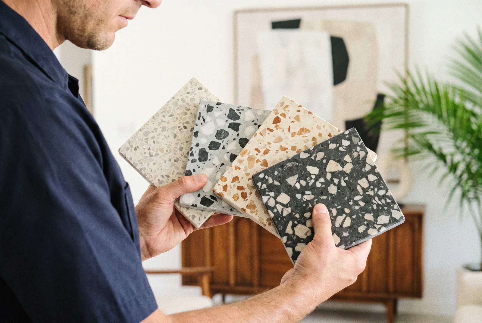 Terrazzo restoration in Tampa: four terrazzo samples held in hand showing different marble and glass aggregate set in the binder