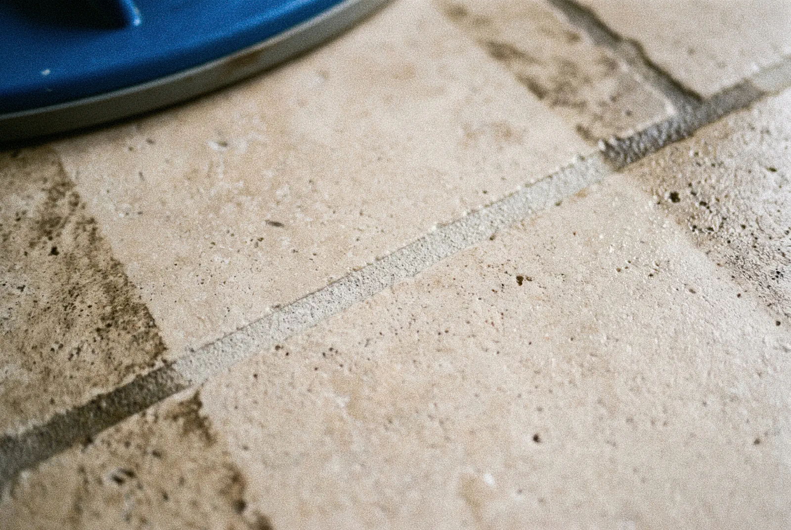 Tile and grout cleaning in Tampa: a spinner tool spraying across dark tile, with cleaned grout lines behind it