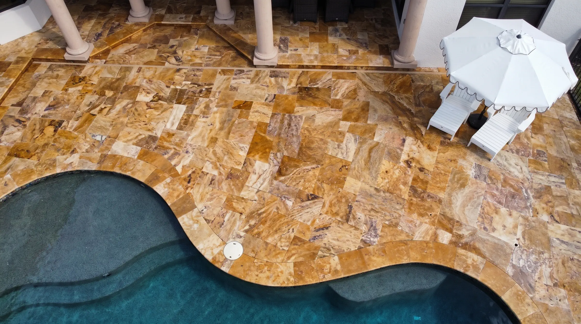 Travertine polishing in Clearwater: a travertine pool deck and coping seen from above at a Clearwater home