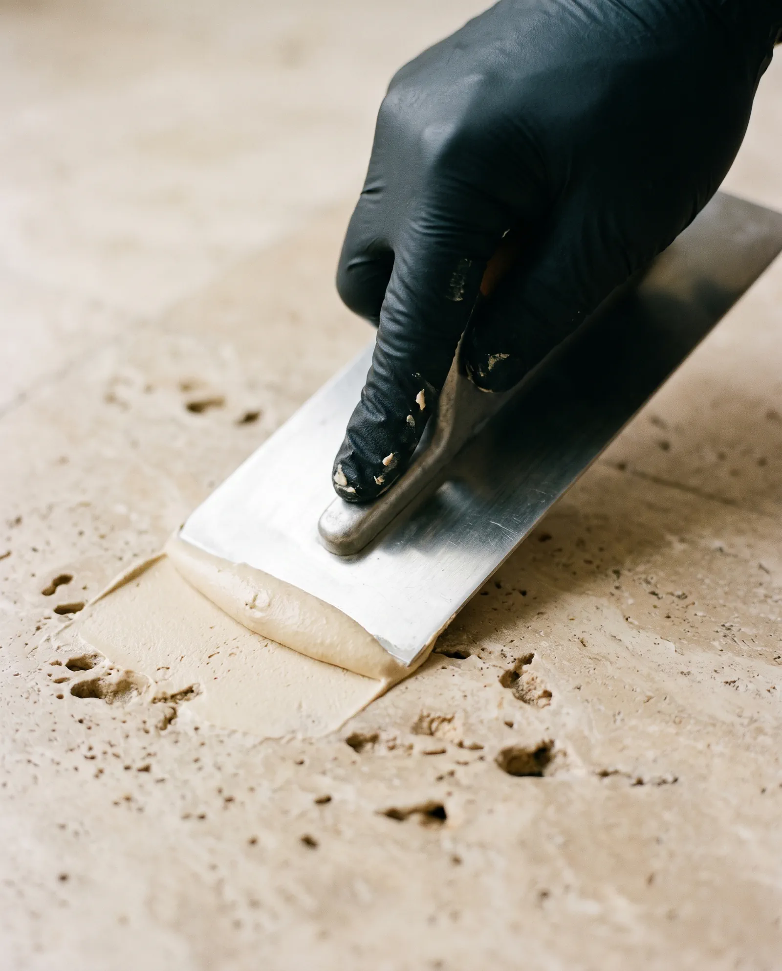 Travertine in Clearwater: fill pressed into open voids on a travertine deck with a flat trowel